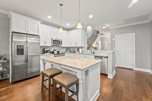 kitchen with white cabinetry, pendant lighting, a kitchen breakfast bar, and appliances with stainless steel finishes