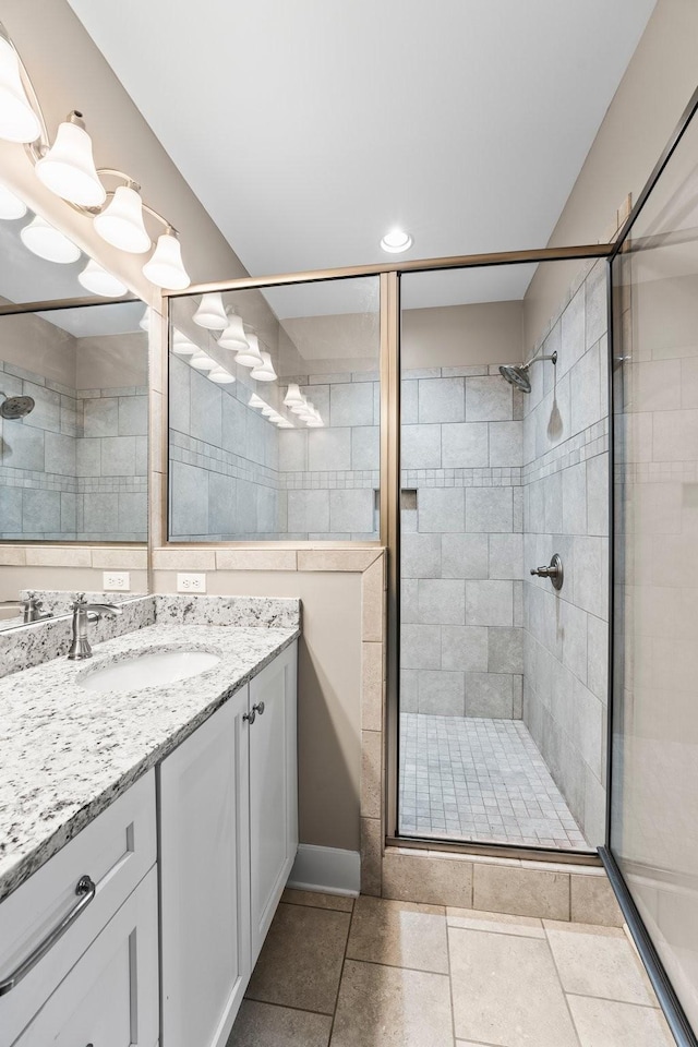 bathroom with tile patterned flooring, vanity, and walk in shower