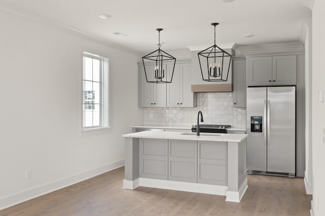 kitchen with pendant lighting, gray cabinetry, tasteful backsplash, a center island with sink, and stainless steel fridge with ice dispenser