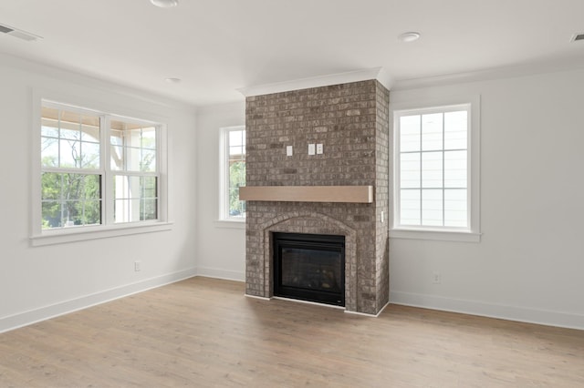 unfurnished living room with wood-type flooring, ornamental molding, and a healthy amount of sunlight