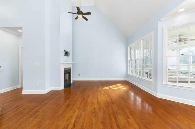 unfurnished living room featuring wood-type flooring, high vaulted ceiling, crown molding, and ceiling fan