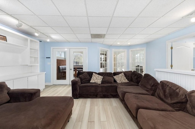 living room with track lighting, a drop ceiling, light hardwood / wood-style floors, and french doors