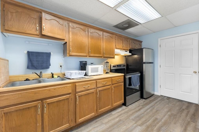 kitchen featuring a drop ceiling, appliances with stainless steel finishes, sink, and light wood-type flooring