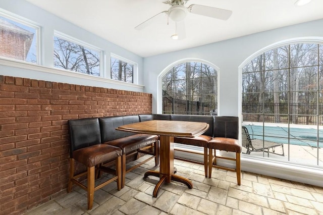 dining area with brick wall and ceiling fan