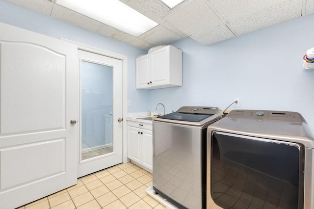 laundry area featuring light tile patterned flooring, cabinets, sink, and washer and dryer