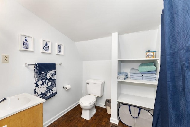 bathroom featuring hardwood / wood-style flooring, vanity, toilet, and vaulted ceiling