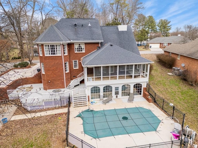 rear view of house featuring a patio area, a sunroom, and a covered pool