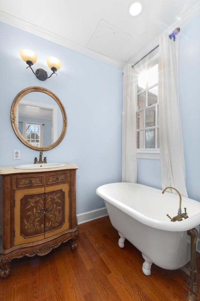 bathroom with vanity, hardwood / wood-style floors, a bathtub, and ornamental molding