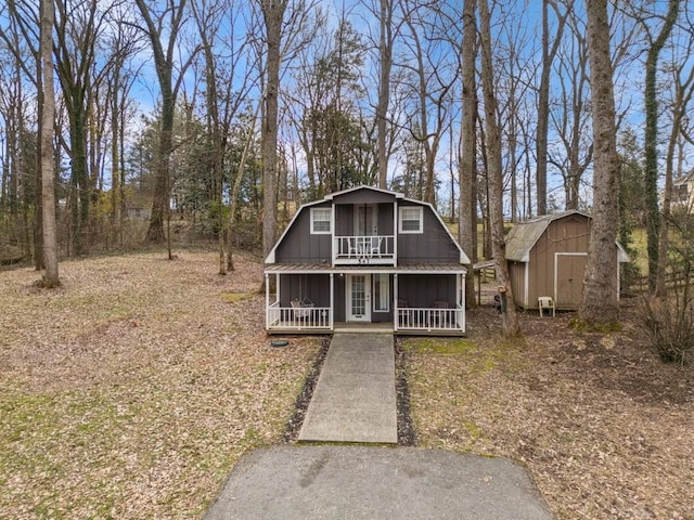 view of front of property featuring a porch and a shed