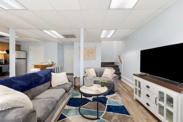 living room featuring a paneled ceiling and light hardwood / wood-style flooring