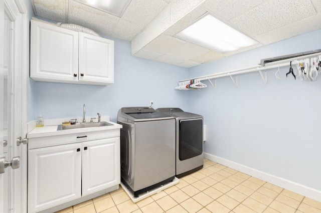 washroom with sink, washer and clothes dryer, cabinets, and light tile patterned flooring