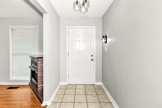 doorway featuring a notable chandelier, a fireplace, and light tile patterned flooring