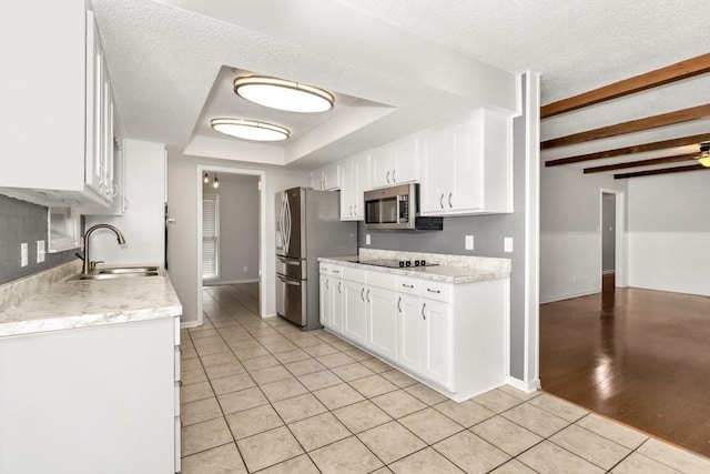 kitchen featuring white cabinetry, sink, light tile patterned floors, stainless steel appliances, and a textured ceiling