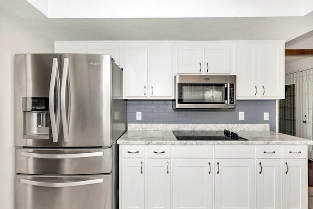 kitchen featuring light stone countertops, a textured ceiling, stainless steel appliances, and white cabinets