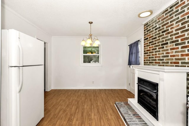 interior space featuring light hardwood / wood-style flooring, a notable chandelier, a textured ceiling, decorative light fixtures, and white fridge