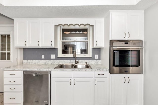 kitchen featuring stainless steel appliances, white cabinetry, sink, and backsplash