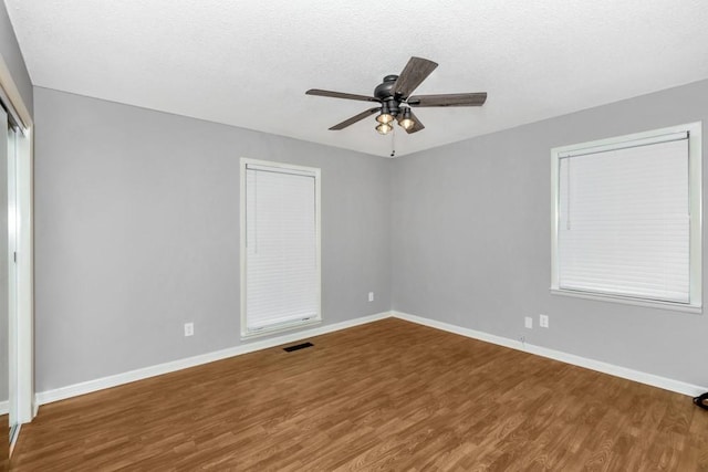 empty room with ceiling fan, hardwood / wood-style floors, and a textured ceiling