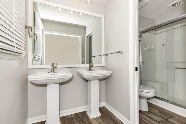 bathroom featuring a shower with door, hardwood / wood-style flooring, sink, and toilet