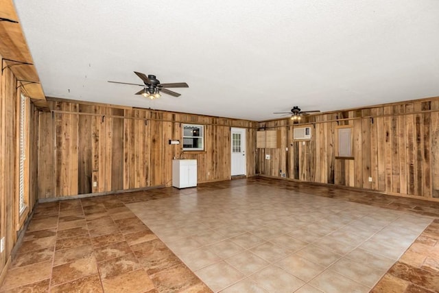 spare room featuring wooden walls, a wall unit AC, and ceiling fan