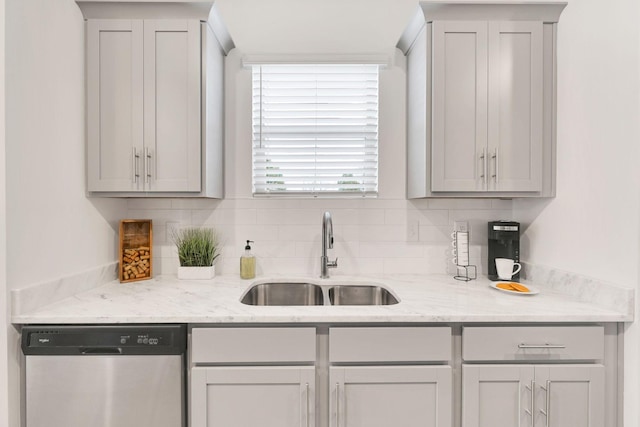 kitchen with dishwasher, sink, light stone countertops, and backsplash