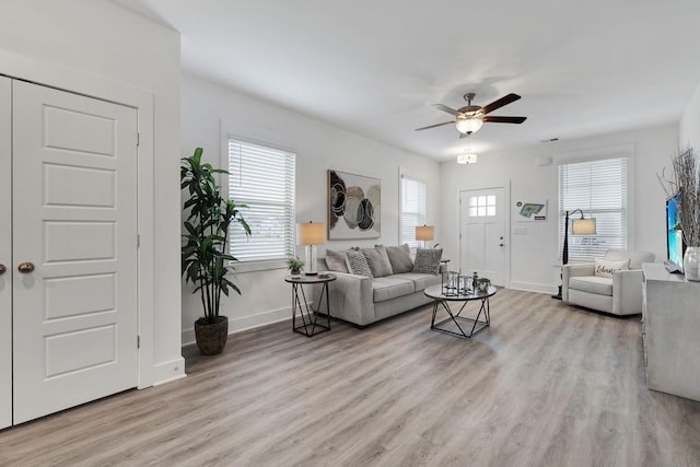 living room featuring ceiling fan, a wealth of natural light, and light wood-type flooring