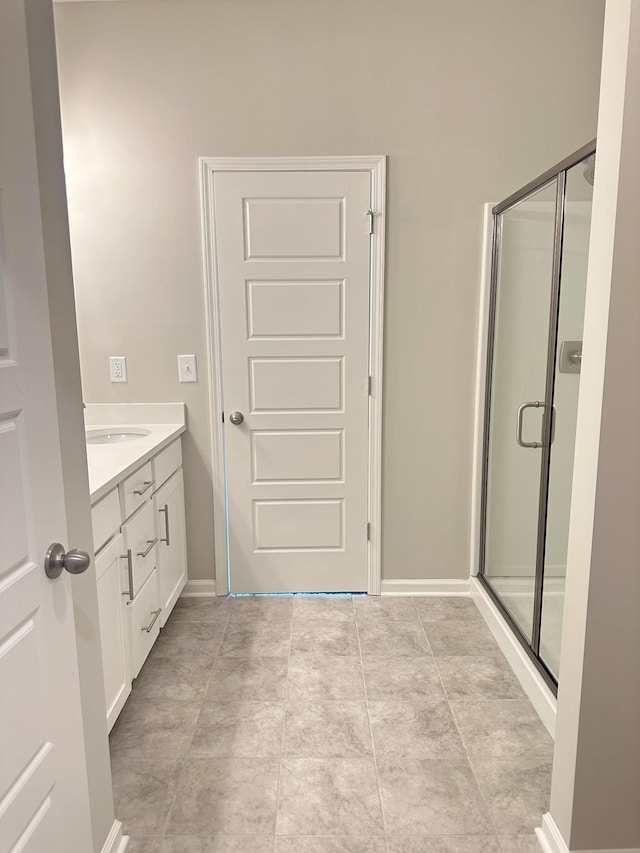 bathroom with a shower stall, vanity, and baseboards