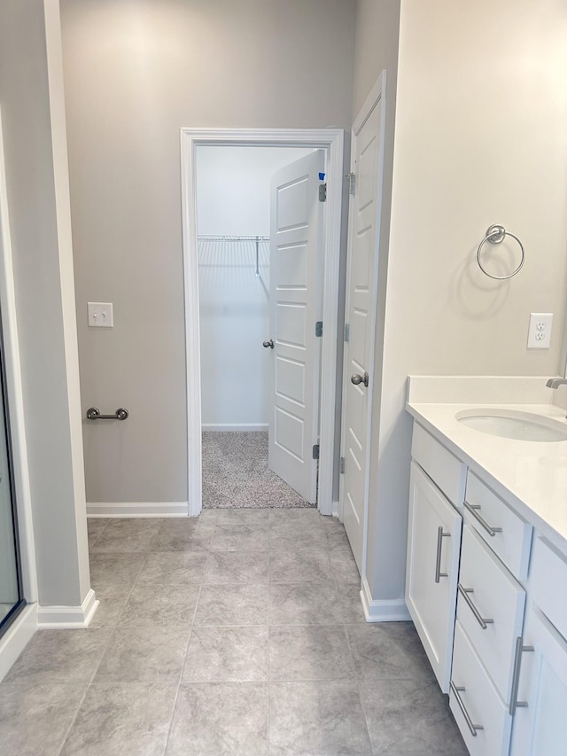 bathroom featuring a walk in closet, baseboards, and vanity