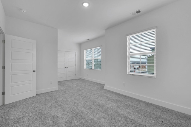 unfurnished bedroom with visible vents, baseboards, a closet, and carpet flooring