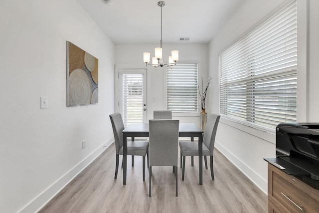 dining area with visible vents, a notable chandelier, light wood-style floors, and baseboards