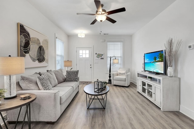 living room featuring ceiling fan, baseboards, and light wood-style floors