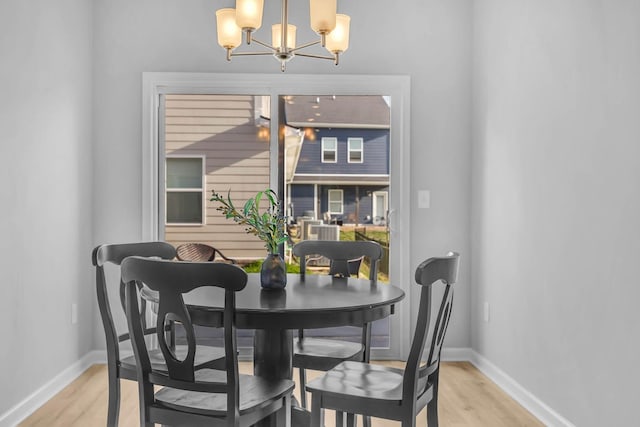 dining space with light hardwood / wood-style flooring and a chandelier