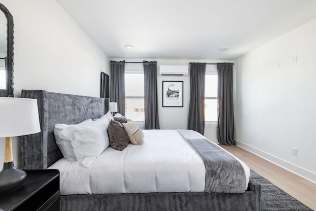 bedroom featuring hardwood / wood-style flooring and an AC wall unit