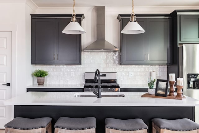 kitchen featuring pendant lighting, a kitchen breakfast bar, stove, a center island with sink, and wall chimney exhaust hood