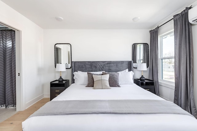 bedroom featuring an AC wall unit and light wood-type flooring