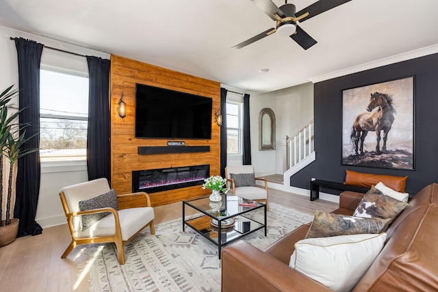 living room with ceiling fan, a wealth of natural light, a fireplace, and light hardwood / wood-style flooring