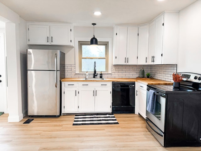 kitchen with stainless steel appliances, white cabinetry, butcher block counters, and decorative light fixtures