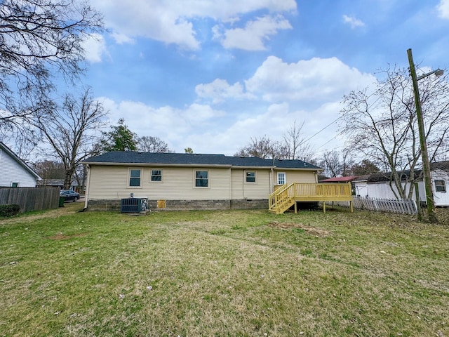 rear view of property featuring central AC unit, a yard, and a deck