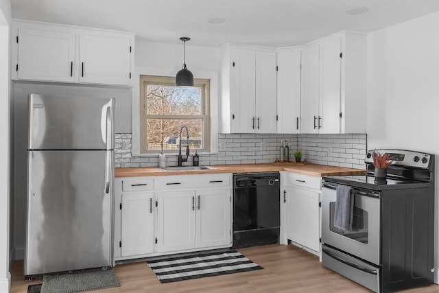 kitchen with butcher block counters, sink, white cabinetry, hanging light fixtures, and stainless steel appliances