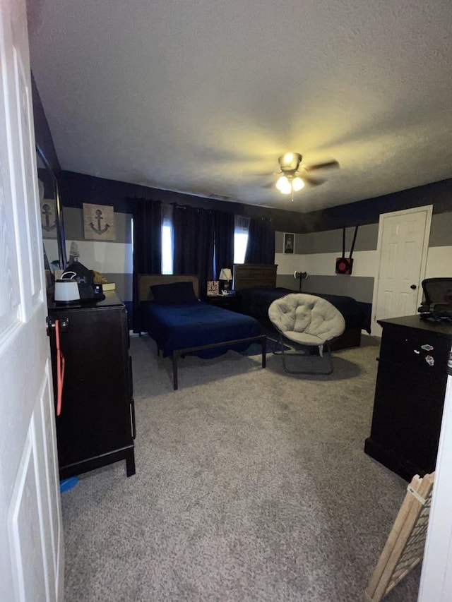 carpeted bedroom featuring ceiling fan and a textured ceiling