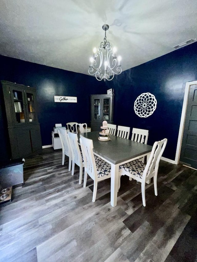 dining space with dark hardwood / wood-style floors and an inviting chandelier