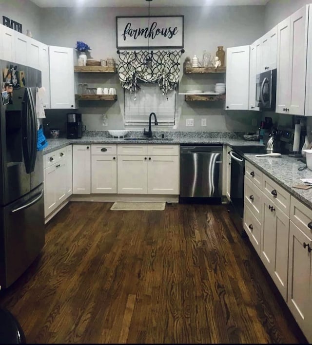 kitchen with white cabinetry, sink, hanging light fixtures, light stone counters, and stainless steel appliances