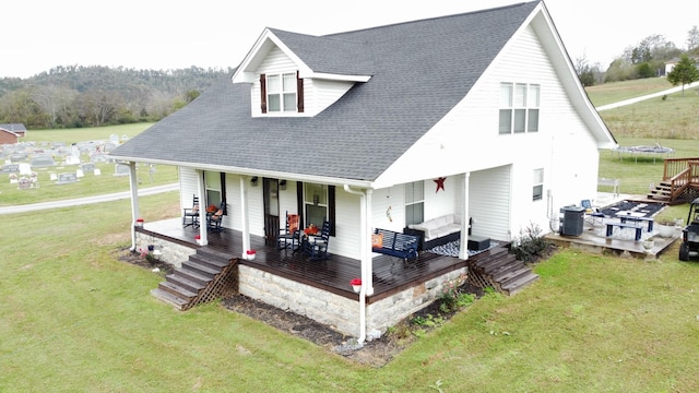 view of front of home featuring a trampoline, cooling unit, a front lawn, and a porch