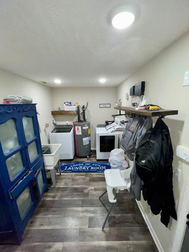 clothes washing area featuring dark hardwood / wood-style floors, a textured ceiling, electric water heater, and washing machine and clothes dryer