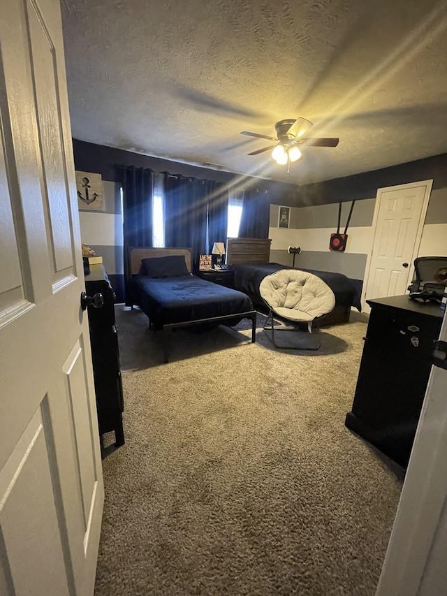 bedroom with ceiling fan, fridge, carpet floors, and a textured ceiling