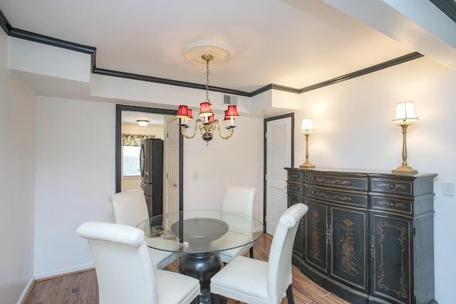 dining room featuring ornamental molding, wood-type flooring, and a notable chandelier