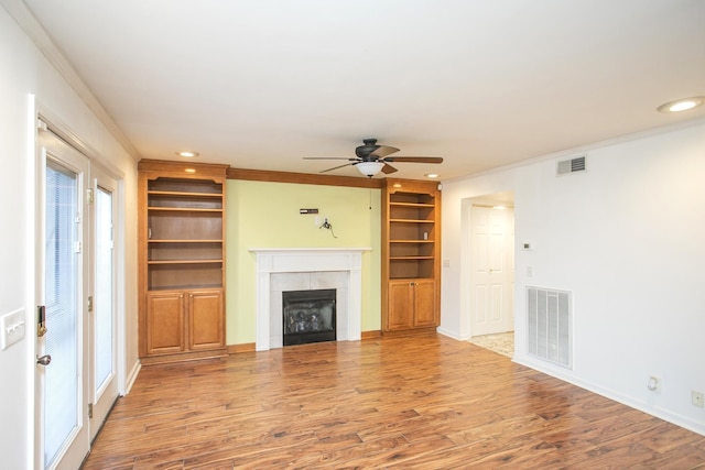 unfurnished living room with a tile fireplace, ornamental molding, hardwood / wood-style floors, and ceiling fan