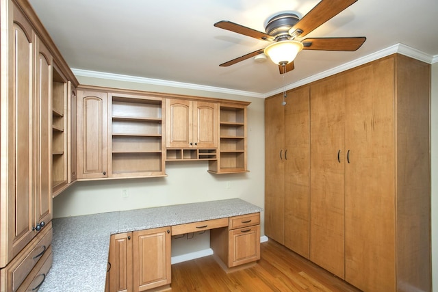 unfurnished office with crown molding, built in desk, ceiling fan, and light hardwood / wood-style floors