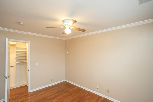 unfurnished bedroom with hardwood / wood-style floors, ornamental molding, a walk in closet, ceiling fan, and a closet