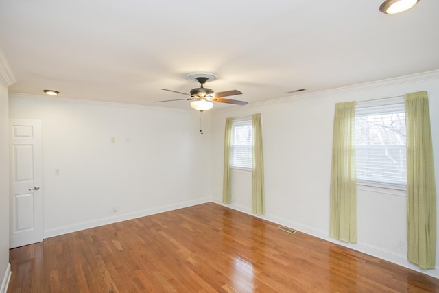 spare room with crown molding, plenty of natural light, and wood-type flooring