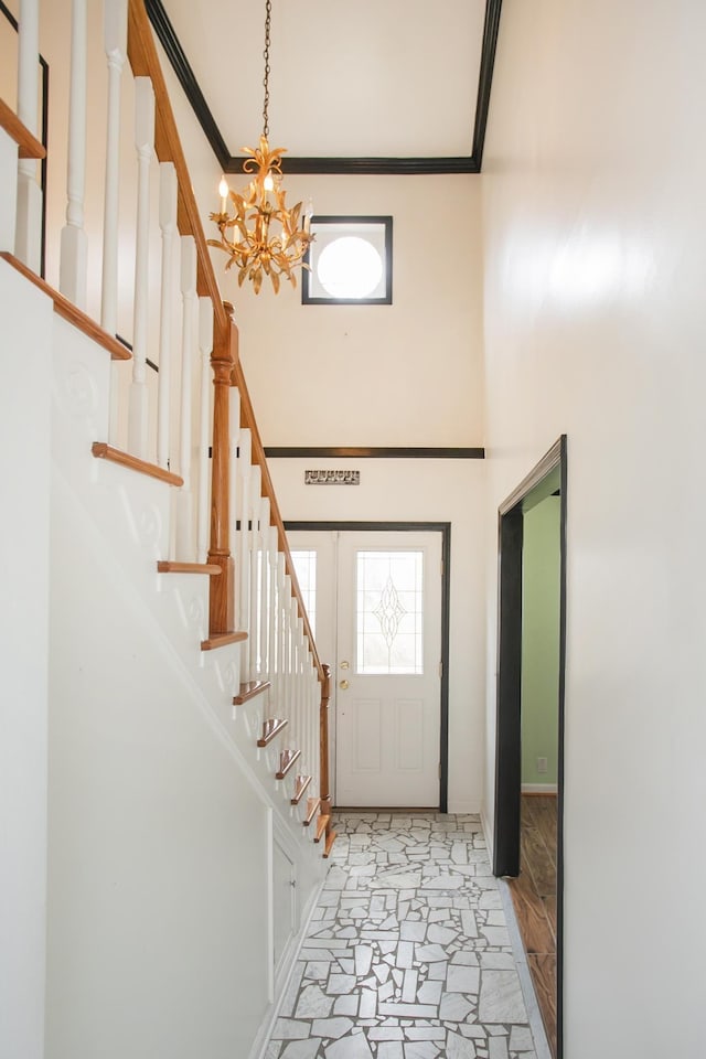 entrance foyer with crown molding, a towering ceiling, and a chandelier